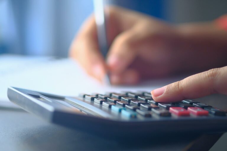 Close-up of a person using a calculator and pen to calculate their superannuation savings and retirement plan.